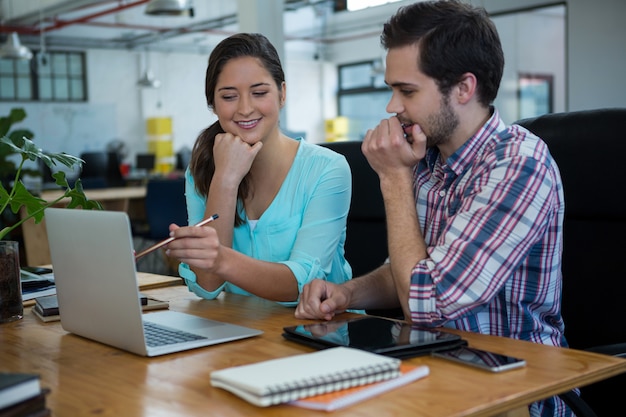 Smiling business executives discussing over laptop