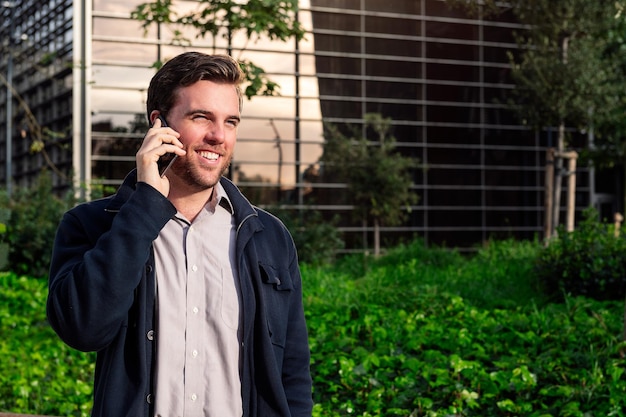 Smiling business man talking by phone in a park