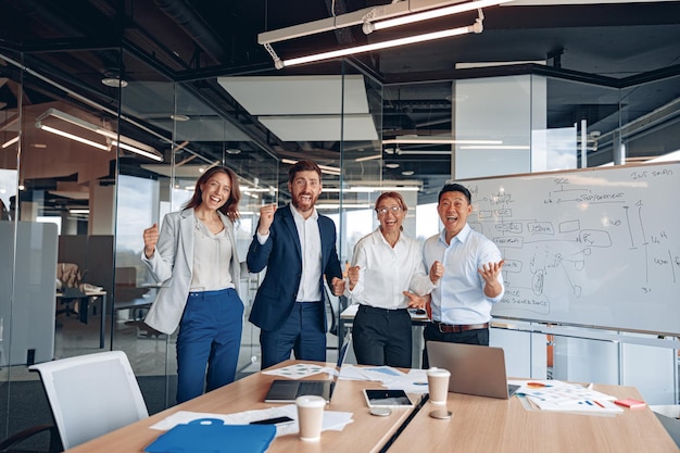 Smiling business men and women in formal clothes happily standing in modern office