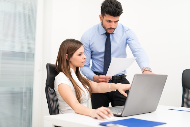 Smiling business people using a laptop computer in their office