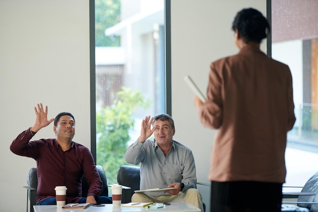 Smiling business people waving to colleague coming to daily meeting in the morning