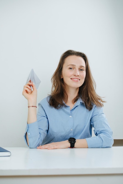 Smiling business woman in blue dress shirt with a paper plane in hand