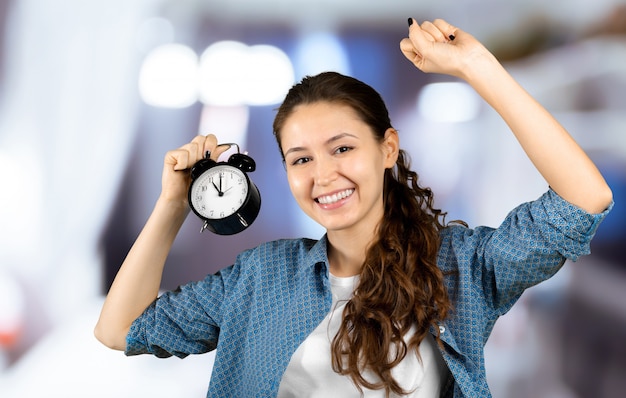 Smiling business woman holding alarm clock. Isolated portrait