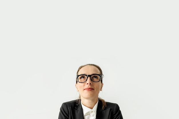 Smiling business woman in a jacket with glasses looks up on a white background