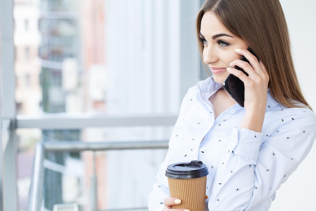 Smiling business woman using phone in office.