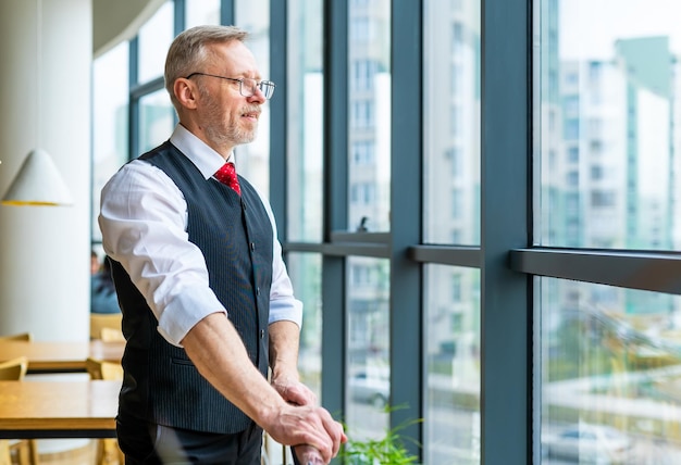 Smiling businessman in gray suit standing and looking in the window Adult man in white shirt with glasess