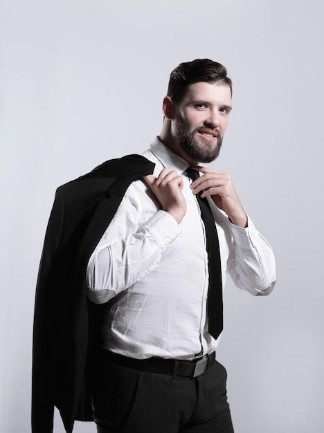 Smiling businessman holding a jacket over his shoulder and straightens the tie