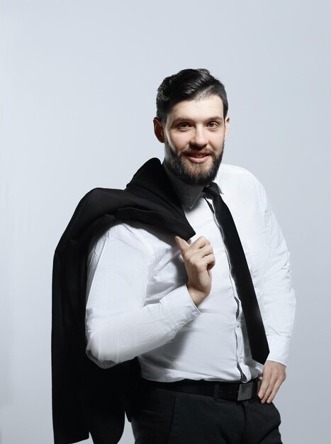 Photo smiling businessman holding a jacket over his shoulder and straightens the tie