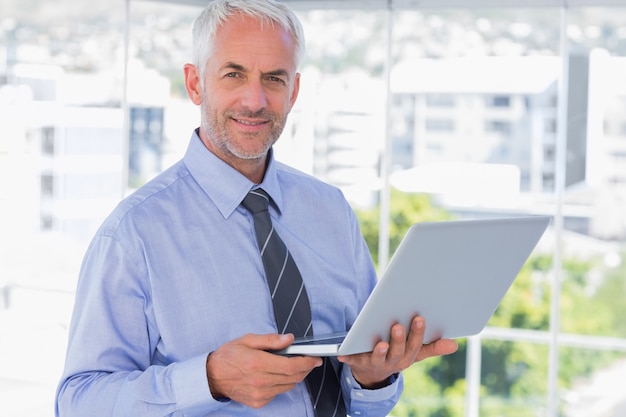 Smiling businessman holding laptop