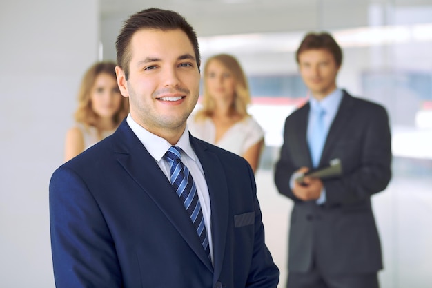 Smiling businessman in office with colleagues in the background