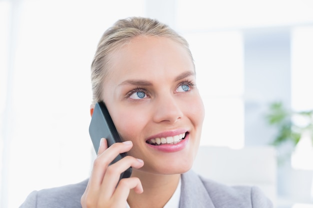 Smiling businessman phoning at her desk 