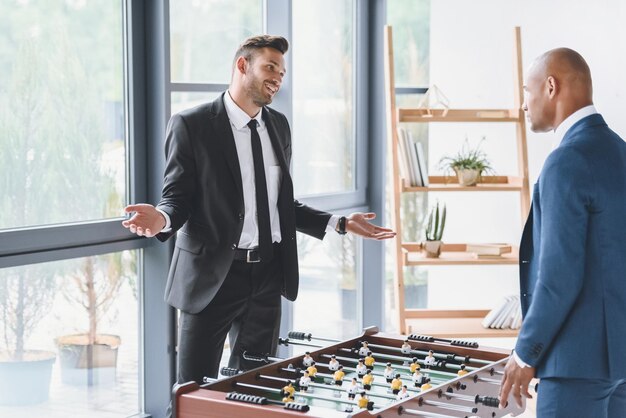 Smiling businessman playing table football with colleague in office