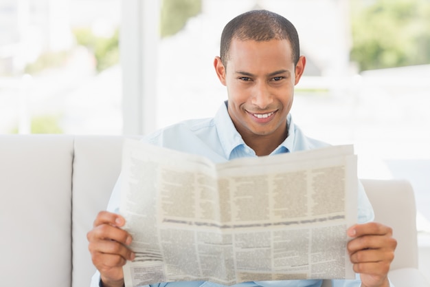 Smiling businessman reading newspaper on the couch