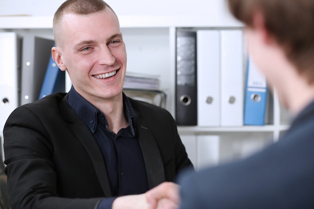 Smiling Businessman  shake hands as hello in office closeup. 