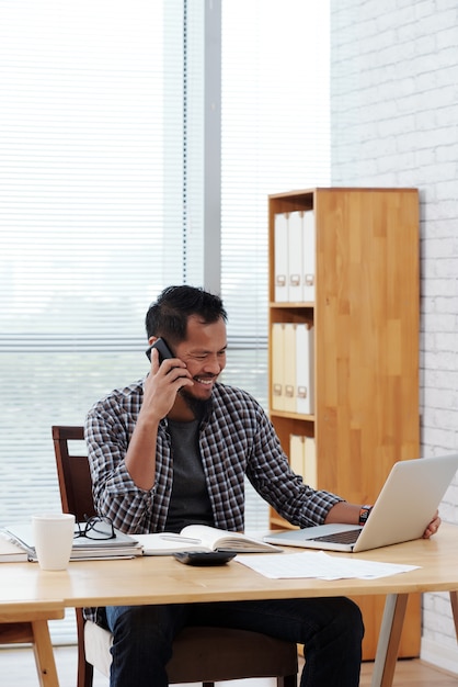 Smiling businessman in shirt working on laptop at his office