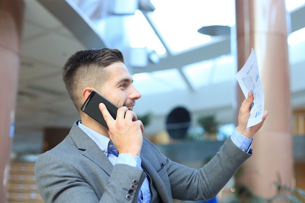 Smiling businessman sitting and using mobile phone in office.