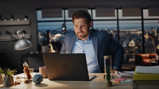 Smiling businessman taking coffee sip office night closeup boss looking laptop