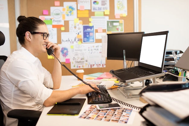 Smiling businessman talking on phone at creative office