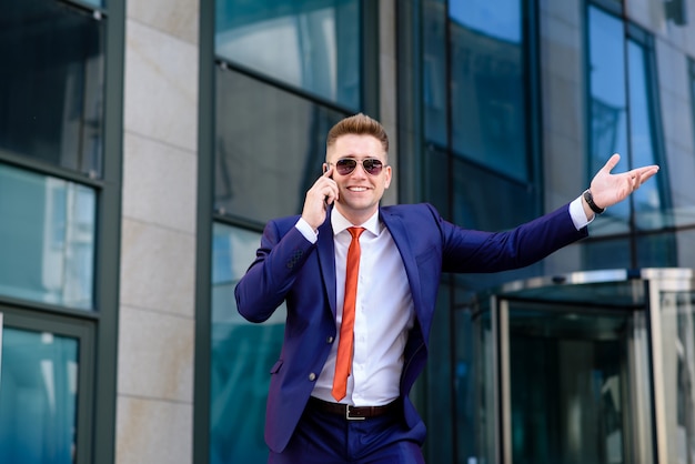 Smiling businessman talking on phone and greeting.