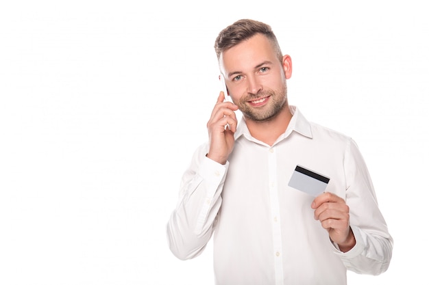 smiling businessman talking on smartphone and holding credit card isolated on white