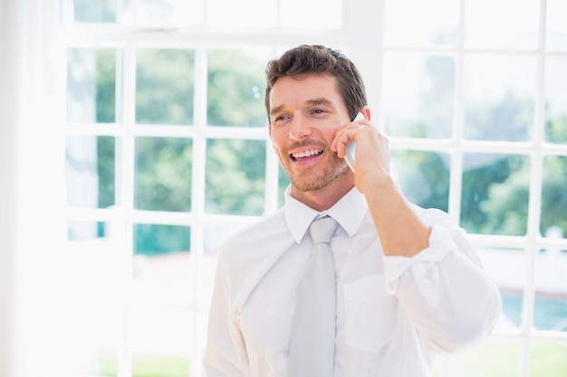 Smiling businessman using mobile phone at home