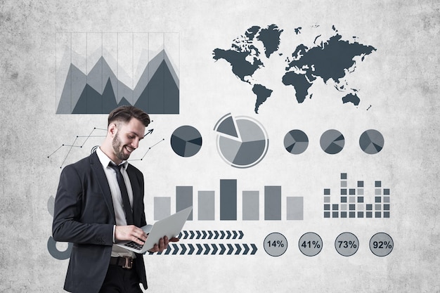 Smiling businessman with a laptop and graphs