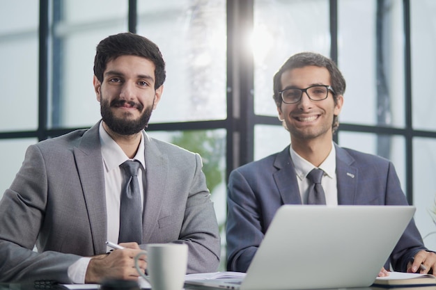 Smiling businessmen with computer in modern office