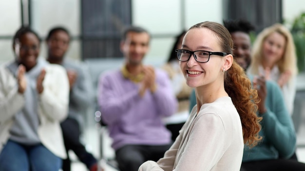 Smiling businesswoman in glasses looking at camera at a seminar