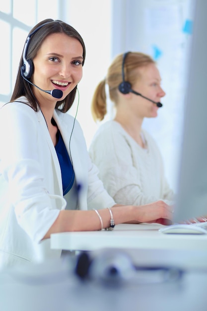 Smiling businesswoman or helpline operator with headset and comp