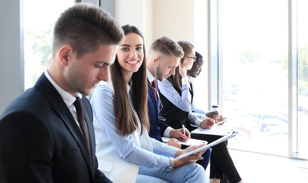 Smiling businesswoman looking at camera at seminar with her colleagues near by