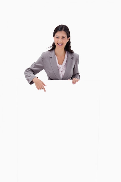 Smiling businesswoman pointing at blank sign