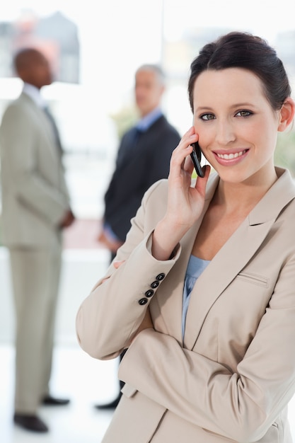 Smiling businesswoman talking on the cell phone while crossing her arms