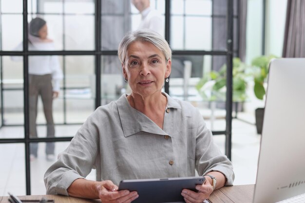 Smiling businesswoman with digital tablet listening during meeting in office