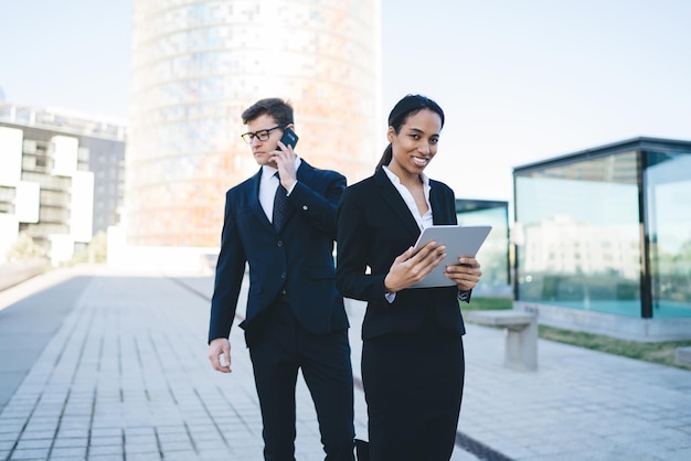 Smiling businesswoman with tablet and colleague on street