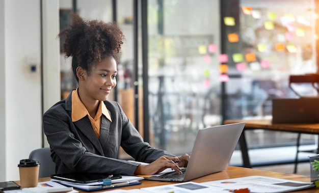 Smiling businesswoman working on laptop in modern open office