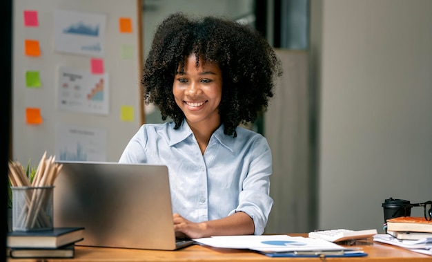 Smiling businesswoman working on laptop in modern open office