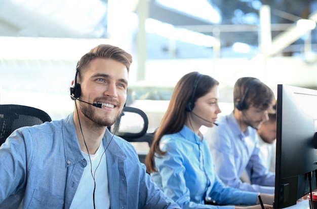 Smiling call center employees sitting in line with their headset.