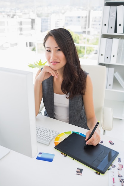 Smiling casual female photo editor using graphics tablet