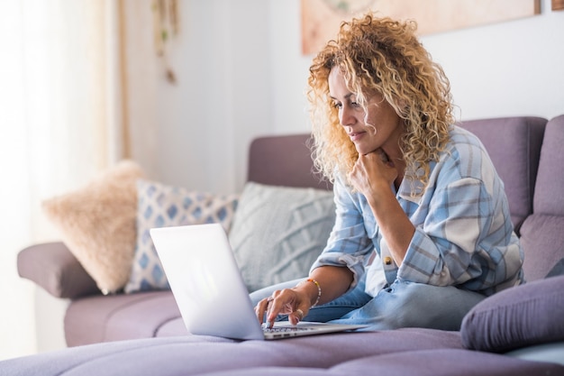 Smiling caucasian adult hipster sit relax on couch using modern laptop browsing unlimited