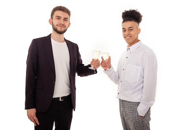 Smiling Caucasian and American gay men standing next to each other drinking champagne from glasses