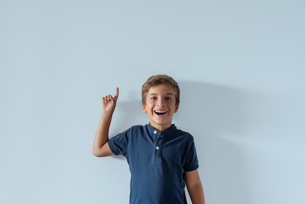 Smiling Caucasian boy pointing his finger upwards Young boy having an idea Event advertisement