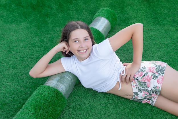 Smiling Caucasian girl lying on a new roll of artificial turf Nice artificial grass ready to lay