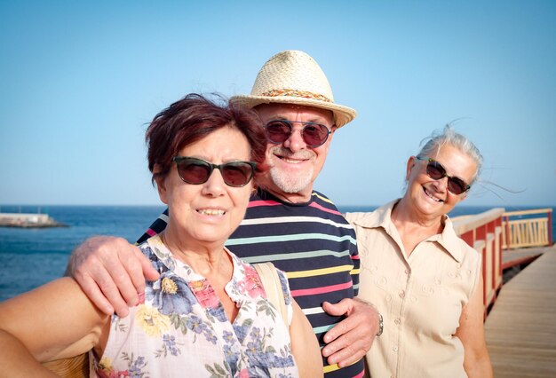 Smiling caucasian group of adult mature people wearing sunglasses enjoying sea vacation good time