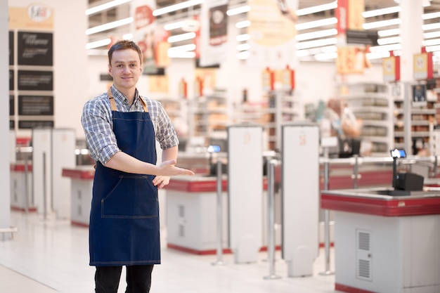 Smiling caucasian salesman invites to store with a gesture