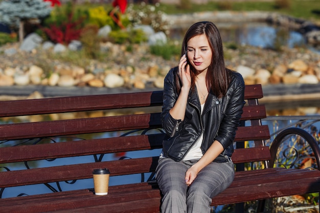 Smiling caucasian woman with mobile phone sitting in park