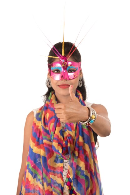 Smiling cheerful girl wearing carnival mask and showing sign isolated on white background