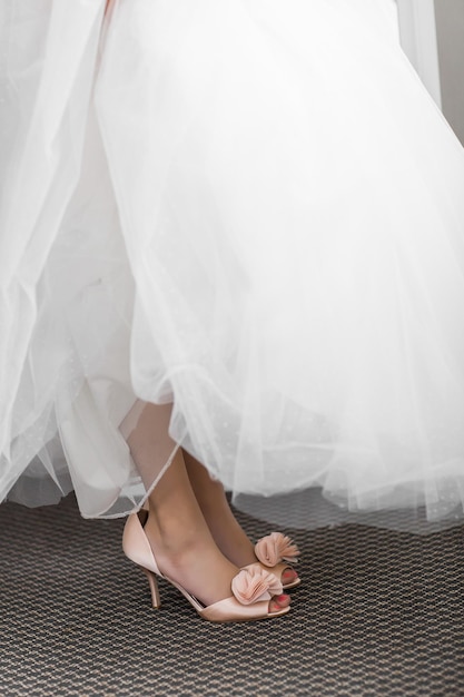 Smiling cheerful little girl in a beautiful white ball gown and sneakers sitting on the stairs to the outdoors