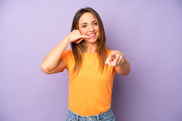 Smiling cheerfully and pointing to camera while making a call you later gesture talking on phone