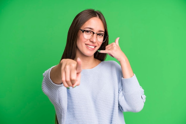 Smiling cheerfully and pointing to camera while making a call you later gesture talking on phone