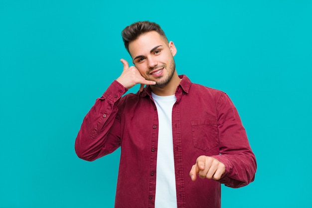 smiling cheerfully and pointing to camera while making a call you later gesture, talking on phone